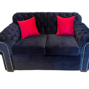 Royal Velvet Chesterfield Sofa in blue velvet with tufted design, nailhead trim, and red accent pillows.